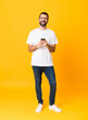 © luismolinero - Full-length shot of man with beard over isolated yellow background sending a message with the mobile