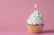 Sweet cupcake with whipped cream and candle on pink background