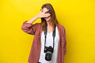 Wall Mural - Young photographer caucasian woman isolated on yellow background covering eyes by hands and smiling