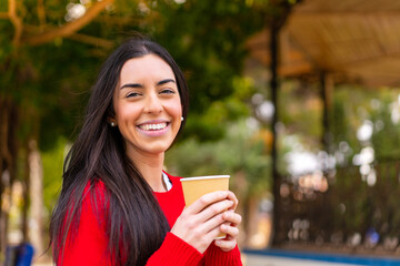 Sticker - Young woman holding a take away coffee at outdoors