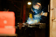 © Zamrznuti tonovi - Man wearing construction gloves and welding mask while welding metal.
