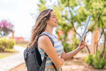 Wall Mural - Young pretty student woman at outdoors with happy expression