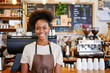 © id512 - young smiling African American female barista standing in her cafe, business concept