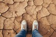 Overhead view of someone standing on parched soil, highlighting environmental concerns and change. Person Standing on Dry Cracked Earth