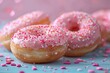 Pink glazed donuts with heart-shaped sprinkles on wooden background