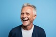 Portrait of happy senior man laughing. Isolated on blue background