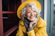 Portrait of smiling senior woman in yellow coat and hat looking at camera