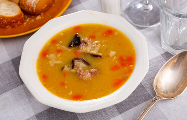 Appetizing hot pea soup with smoked meats served with slices of bread