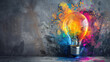 A colorful light bulb is lit up against a gray background. The light bulb is surrounded by a splash of paint, giving the impression of a creative and artistic scene.