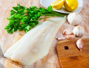 Wall Mural - Seafood ingredients, fresh cod-like fish on wooden cutting background