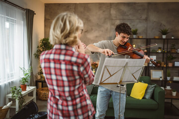 Young man learn how to play violin under instruction mature professor