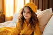 beautiful little girl in a yellow hat and pajamas on the bed