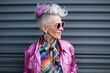 Fashionable senior woman in pink jacket and sunglasses on a gray background