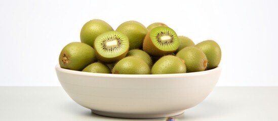 Canvas Print - A white mixing bowl with fresh green kiwi fruit, a staple food in the Olive family, on a table creating a natural and nutritious dish