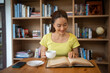 Young woman reading book and drink hot coffee in library at home, smiling, laughing, enjoying bookworms hobby, home leisure time