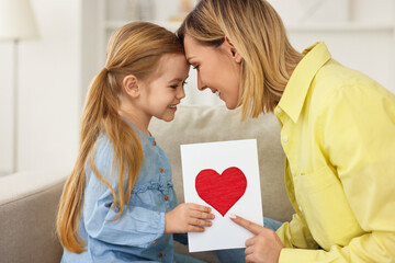 Wall Mural - Little daughter congratulating her mom with greeting card at home. Happy Mother's Day