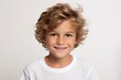 Portrait of a cute little boy with blond curly hair on a gray background