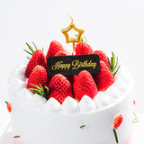 Fototapeta Zachód słońca - Delicious birthday cake with fresh strawberries, on wooden table and white background. Free space for your text.