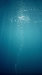 Poster - Sunlight beams filter through the deep, crystal-clear, blue-turquoise water, casting a beautiful curtain of reflections. Air bubbles rise gracefully towards the water's surface, adding to the pictures