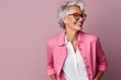 Portrait of a happy senior woman with eyeglasses over pink background