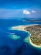 Aerial view of a tiny tropical island surrounded by large, fringing coral reef and blue, warm ocean (Gili Air, Indonesia)