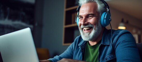 Poster - An older man with a beard and eyewear is smiling while using audio equipment and a laptop computer. He seems to be having fun with his gadget and output device