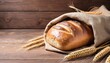 bread loaf and wheat ears and sack on wooden background.