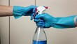 hand in blue rubber gloves holding spray bottle