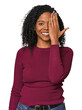 African American woman in studio setting having fun covering half of face with palm.