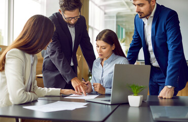 Wall Mural - Group of business people or company employees sitting at the desk discussing something on workplace, reaching agreement and signing a contract. Coworkers having a meeting in office.