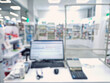 © airlifting - Defocused view inside of pharmacy with the seller counter, computer and cash register against stocked shelves with medicines. Healthcare and cosmetics industry blurred background