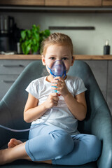 Cute little girl are sitting and holding a nebulizer mask leaning against the face at home on sick leave, airway treatment concept