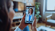 © Kien - A closeup of an adult woman's hand holding her smartphone, with the screen showing a video call between two women in white coats and glasses on their faces