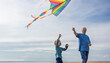 © Westend61 - Elderly man flying kite with grandson at beach