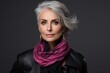 Fashionable senior woman with grey hair and pink scarf. Studio shot.
