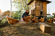 Happy middle aged woman on a private farm feeding chickens. Eco-friendly farmer woman cares, looks after her chickens in her backyard, promoting organic poultry farming