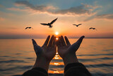 Fototapeta  - Hands outstretched upwards in a gesture of worship against a serene sunset over water, with birds soaring above. Symbolizing prayer and seeking divine blessings