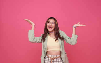 Happy Asian woman presenting or showing open hand palm with copy space for product isolated on pink background