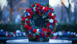 A wreath of red, white, and blue flowers is placed on a table