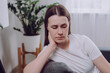 Confused young woman feels unhappy, problems in personal life, quarrel break up with boyfriend and unexpected pregnancy concept. Anxious worried caucasian female sitting alone on sofa at home