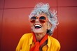 Portrait of a happy senior woman in sunglasses against a red background