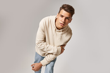 Wall Mural - handsome young man leaning to forward and holding to arm against grey background