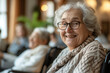 Portrait of happy retired senior woman sitting at nursing home. Satisfied old woman looking at camera and smiling while relaxing with friends. Positive and confident elderly enjoy his retirement.