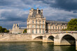 Palais du Louvre and Pont Royal on Seine River under heavy cloud at golden hour - Paris, France