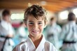 © PhotoPhantom - A joyful European boy in a martial arts uniform looks at the camera during a Judo or Karate class