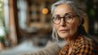  portrait of serious positive old mature woman with glasses in casual looking at camera, posing at home
