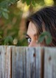 woman nosey neighbor peaking over fence. Side eye to camera. Can only see too half of face