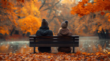 A Young Man And A Girl Sitting On A Bench In An Autumn Park Near A Pond