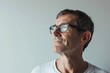 © Iigo - Portrait of handsome senior man in glasses looking away while standing against grey background