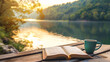 An open book and a coffee cup are placed on a wooden table next to a beautiful river view in dusk time as a background with a relaxed ambience. Background for relaxation, vacation and rest time.